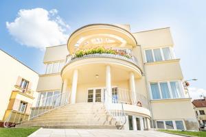 鲁哈科维斯Vila EVA的一座大型白色建筑,设有阳台和楼梯