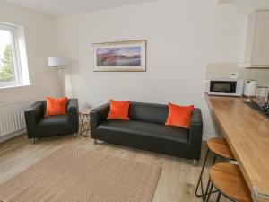 a living room with a black couch and orange pillows at One Conway View in Colwyn Bay