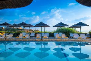 a group of chairs and umbrellas next to a swimming pool at Blue Bay Resort Hotel in Agia Pelagia