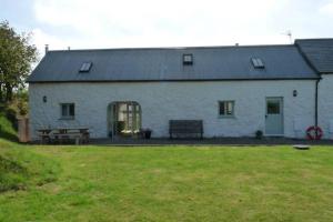 ein weißes Gebäude mit einem Picknicktisch und einer Bank in der Unterkunft The Barn @ Mill Haven Place, 3 bedroom cottage in Haverfordwest