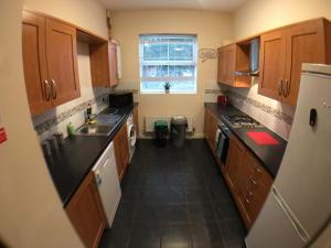 波士顿Very LARGE House, 6 beds, 4 bedrooms, 3 Bathrooms, 5 Smart TV's & VAN PARKING的厨房设有木制橱柜和黑色地板。