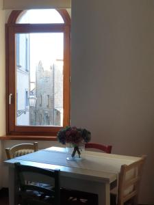einen Tisch mit einer Blumenvase und einem Fenster in der Unterkunft Appartamento Mia in Orvieto