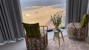 una camera con due sedie e vista sulla spiaggia di Maritimo Luxury ApartHotel a Constanţa