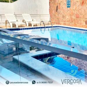 una piscina con acqua blu e sedie bianche di Pousada Verçosa - Rota Ecológica dos Milagres a Passo de Camarajibe