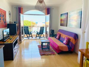 Puerto de las LajasにあるFuertelena Sunrise Lovers Apartmentのリビングルーム(ソファ、テレビ、バルコニー付)