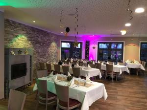 a restaurant with white tables and chairs and pink lighting at Hotel Am Park in Pasewalk