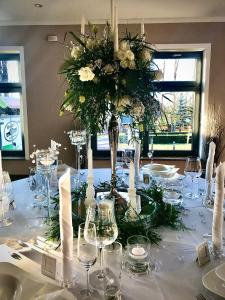 einen Tisch mit einem Herzstück von weißen Blumen und Kerzen in der Unterkunft Hotel Am Park in Pasewalk