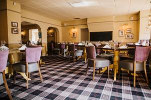 a dining room with tables and chairs and a tv at The Stratton House Hotel in Biggleswade