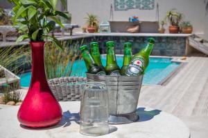 un cubo de botellas de cerveza en una mesa junto a un jarrón en The Beach House Guest House, en Hout Bay