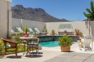 a patio with a table and chairs next to a pool at The Beach House Guest House in Hout Bay