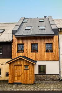 a wooden house with a black roof at Apartmány Kůlna in Boží Dar