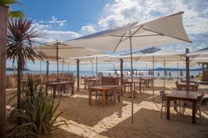 a group of tables and chairs under an umbrella on the beach at Holidays by juliano camping 5 etoiles 3149 in Grimaud