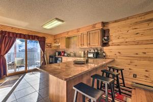 a kitchen with wooden cabinets and a island with bar stools at Downtown Red River Retreat with Mtn Views and Yard in Red River
