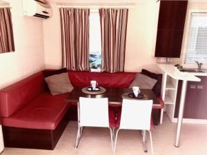ein Wohnzimmer mit einem roten Sofa, einem Tisch und Stühlen in der Unterkunft Holidays by juliano camping 5 etoiles 3149 in Grimaud