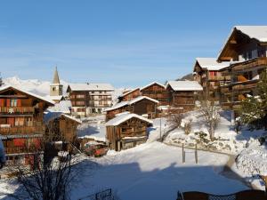 un pueblo cubierto de nieve con edificios de madera y una iglesia en apartment EGGERI - das sportliche en Grächen