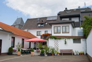 Casa blanca con patio con sombrilla roja en Ferienwohnung Hörning, en Roxheim