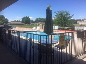 ein Pool mit einem Sonnenschirm, 2 Stühlen und einem Tisch mit einem Sonnenschirm in der Unterkunft Quality Inn Siloam Springs West in Siloam Springs