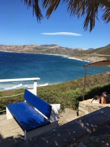 um banco azul sentado num convés a olhar para o oceano em Villa grand confort à 500m de la plage de LOZARI em Palasca
