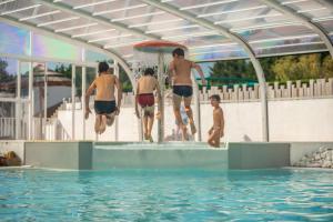 un grupo de chicos saltando a una piscina en Camping Les Brillas, en Les Moutiers
