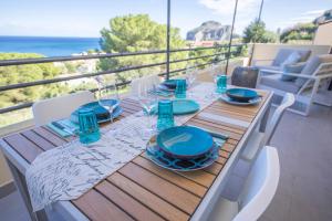 een houten tafel met blauwe borden en glazen op een balkon bij Ilenia Seaview in Cefalù