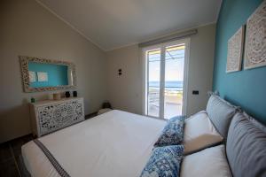 een slaapkamer met een bank en een raam met uitzicht op de oceaan bij Ilenia Seaview in Cefalù