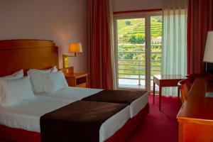 a hotel room with a bed and a balcony at Hotel Regua Douro in Peso da Régua
