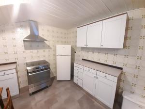 una cucina con armadi bianchi e piano cottura di Ampia Mansarda a Dimaro in Val di Sole a Monclassico