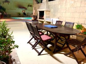 a wooden table and chairs in a patio with a fireplace at Classic Farmhouse & Private Pool in Mġarr