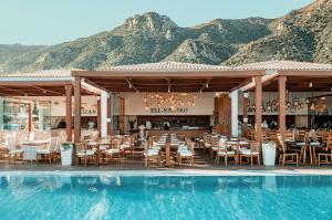 a restaurant with a swimming pool next to a mountain at Mitsis Selection Blue Domes in Kardamaina
