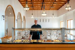 a man standing behind a buffet of food at Mitsis Selection Blue Domes in Kardamaina