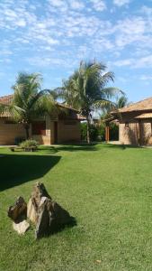 a house with palm trees and a rock in a yard at Pousada Cheiro de Mato in Bonito