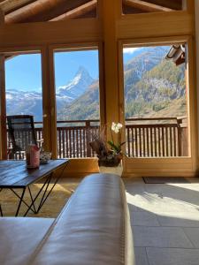 a living room with a table and a view of mountains at Chalet Conthey in Zermatt