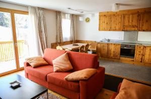 a living room with a red couch and a kitchen at Ca del Forno St Moritz in Maloja