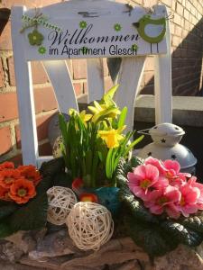 a sign with some flowers in front of a chair at Apartment Glesch in Bergheim