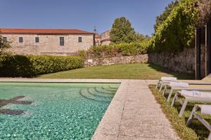 - une piscine avec 2 chaises longues à côté d'un bâtiment dans l'établissement Eurostars Monumento Monasterio de San Clodio Hotel, à Leiro