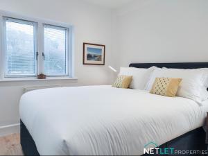 7 Orion House, Milford Haven في ميلفورد هافن: سرير أبيض كبير في غرفة بها نوافذ