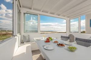 uma sala de jantar branca com uma mesa com comida em Naxian Wave Seaside Villa em Mikri Vigla