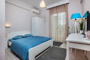 a white bedroom with a blue bed and a desk at St Paul House in Thessaloniki