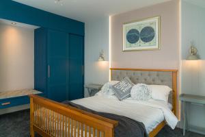 a bedroom with a large bed with blue walls at Finest Retreats - The Stables at Crimplesham in Stradsett