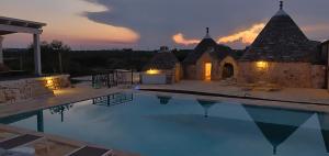 eine Villa mit einem Pool bei Sonnenuntergang in der Unterkunft Trullo la perla di pietra in Alberobello