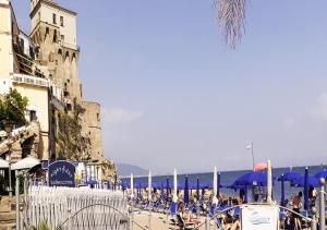 a beach with blue umbrellas and people on the sand at Casa Rosa appartamento con giardino in Cetara +11 photos
