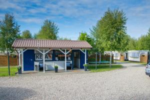 a small blue building with a bench in a driveway at Keja Domki Chłapowo in Władysławowo