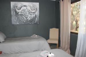 a bedroom with two beds and a painting on the wall at Wilgeboomsdrift Safaris in Modimolle