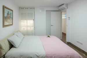 a bedroom with a white bed with a pink blanket at Apartamento Avenida Principal I in Altea