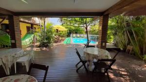 a patio with tables and chairs and a swimming pool at Pousada Palhocinha Garopaba in Garopaba