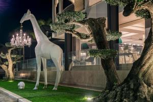 une statue d'une girafe debout à côté de quelques arbres dans l'établissement Hotel Cerere, à Paestum