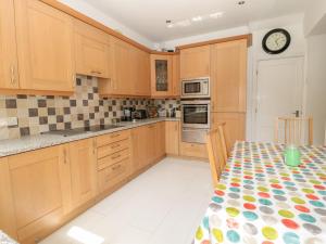 a kitchen with wooden cabinets and a table with a clock at 1A Chantry Place in Morpeth