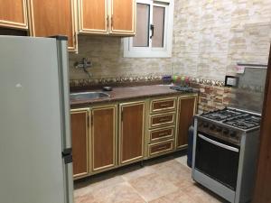 a kitchen with wooden cabinets and a sink and a stove at Maadi Ring Road Sweet Apartment in Cairo