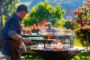 a man is cooking food on a grill at Hotel Semriacherhof in Semriach
