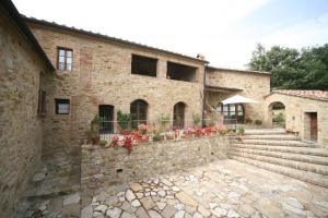 un grand bâtiment en briques avec des fleurs sur un mur en pierre dans l'établissement Agriturismo Podere Costarella, à Radicondoli